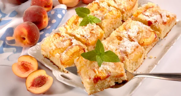 Sočne rezine z breskvami na puhastem biskvitu